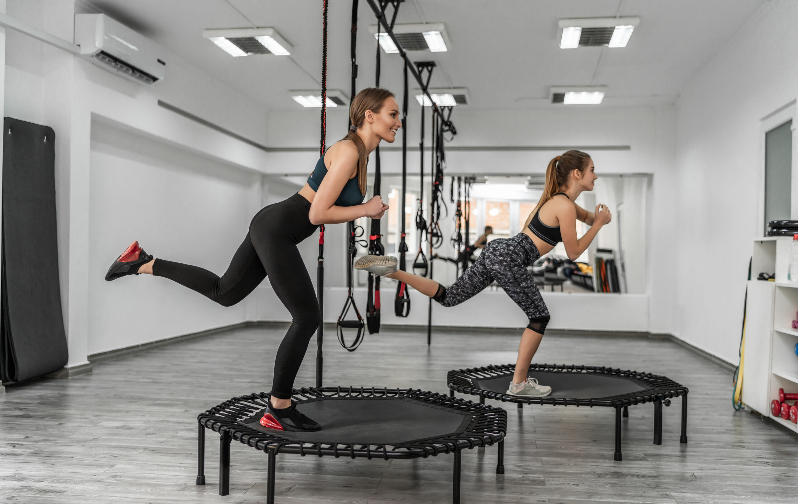 Portrait of a group two girls in gymnastics fitness trampolines Zwei Frauen trainieren auf Mini-Trampolinen in einem Fitnessstudio