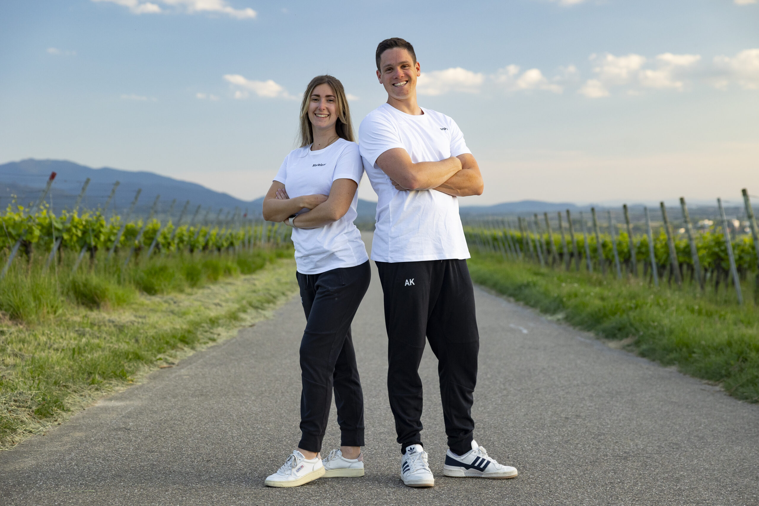 TVMerch-06 Zwei Vereinsmitglieder in weißen TV-Shirts auf einem Weg durch die Weinberge