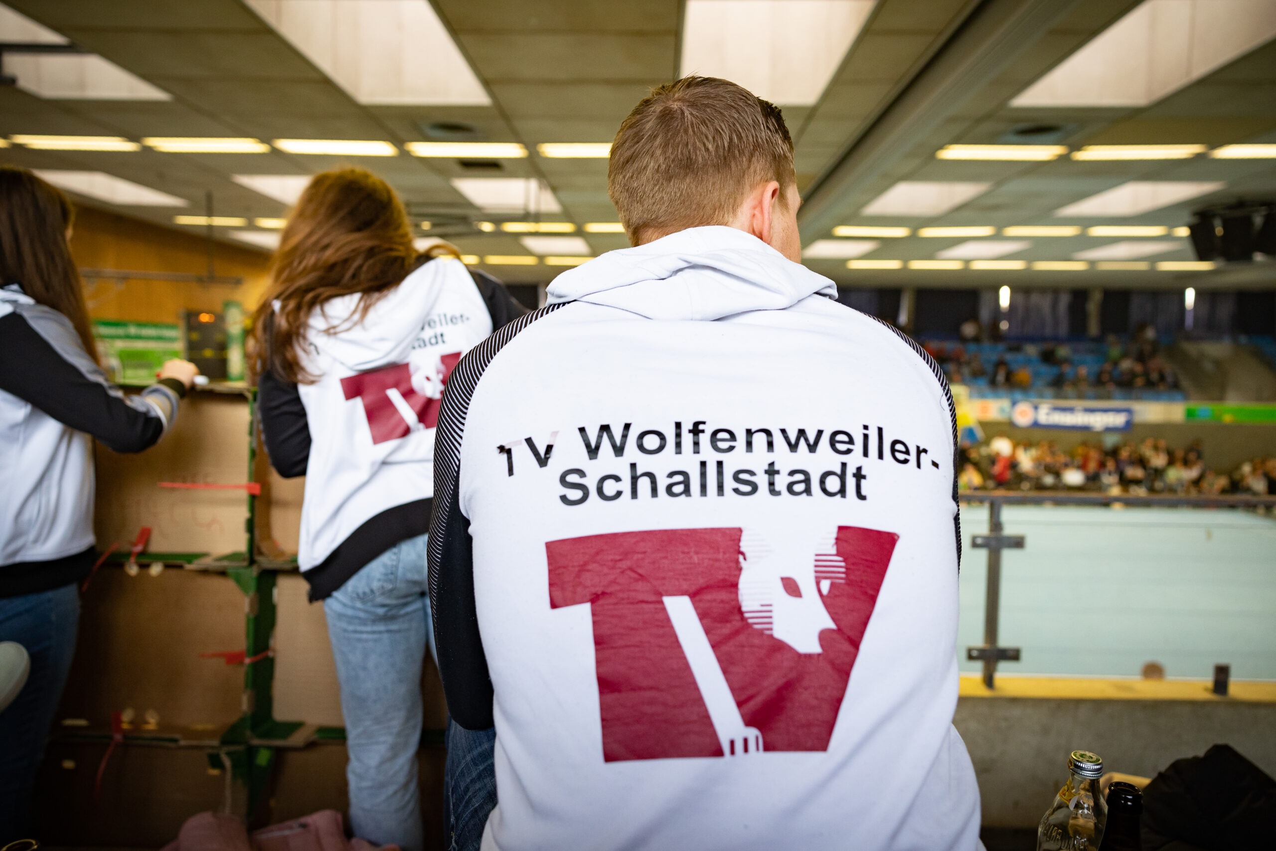 Verein Gruppe junger Sportlerinnen und Sportler von hinten in Vereinsjacken mit Aufschrift TV Wolfenweiler-Schallstadt